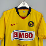 2008/09 Club America home shirt by Nike in medium size, yellow with logo and sponsor, showing excellent condition.